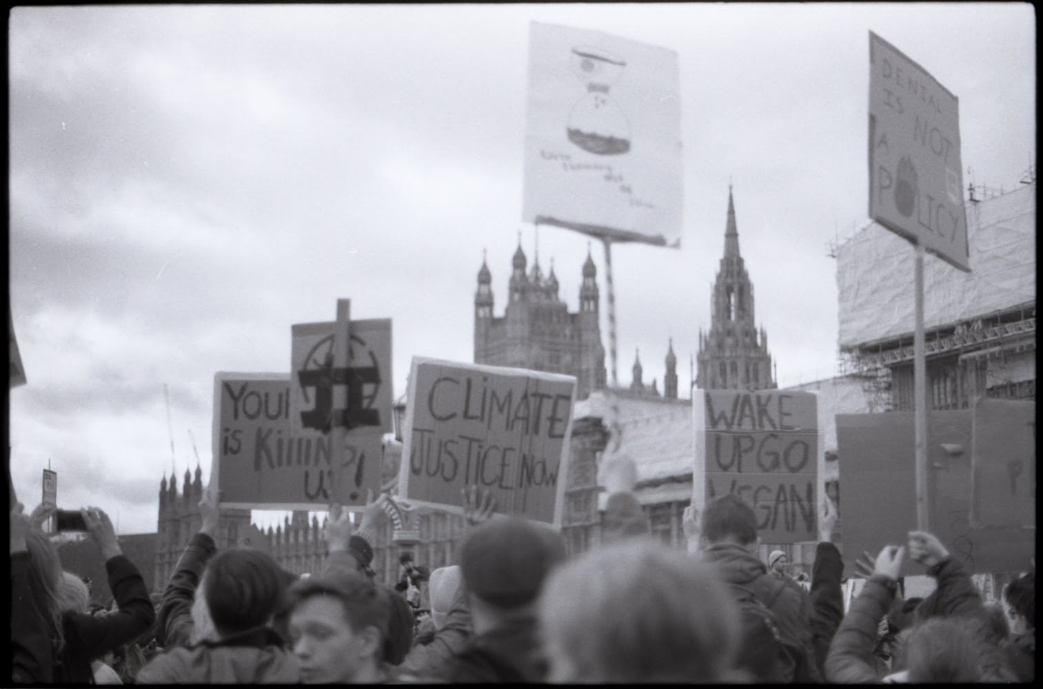 a crowd holding up banners in front of the parliament skyline